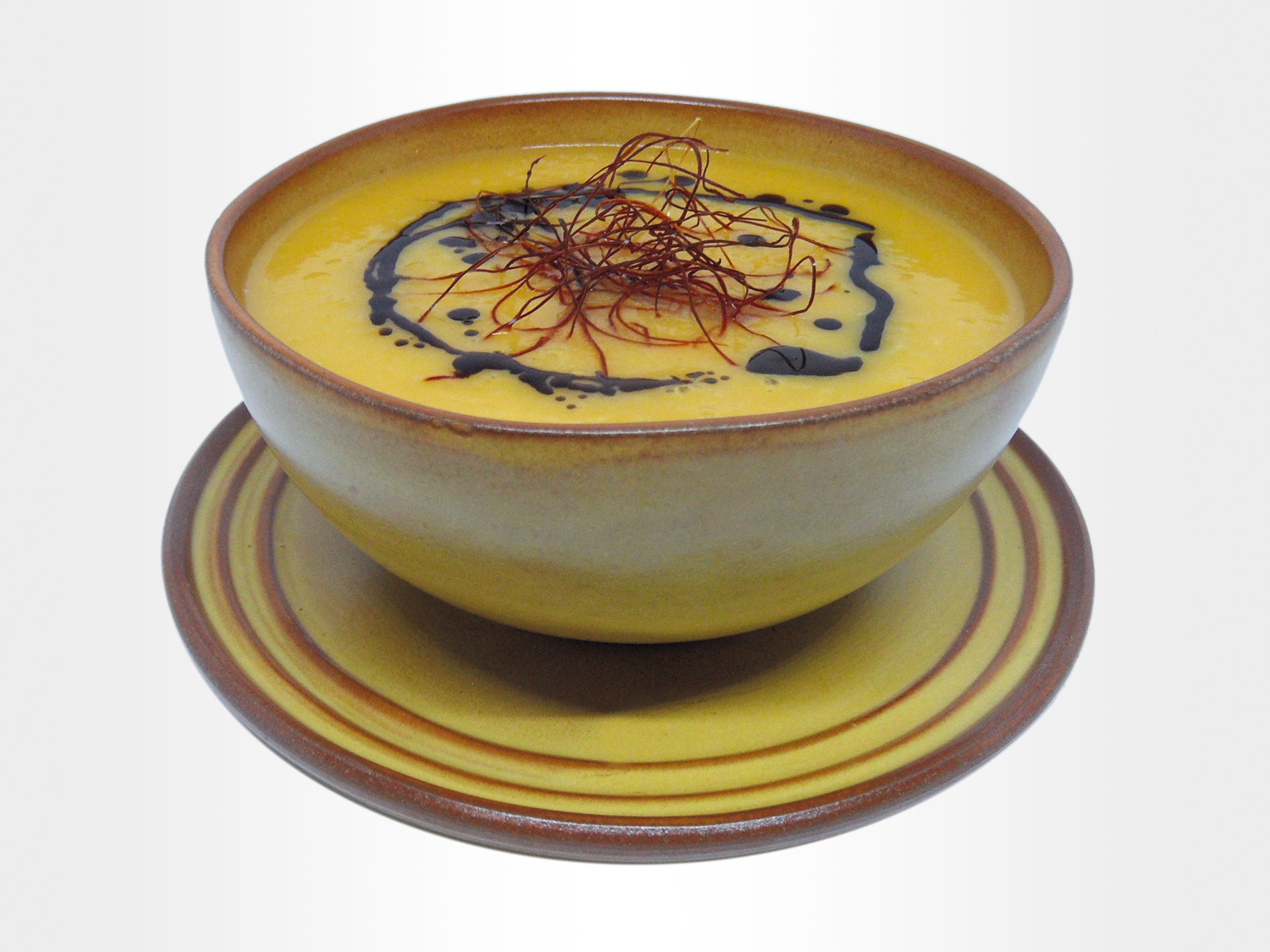 zdjelica s juhom od bundeve ukrašenom bučinim uljem i nitima od čilija